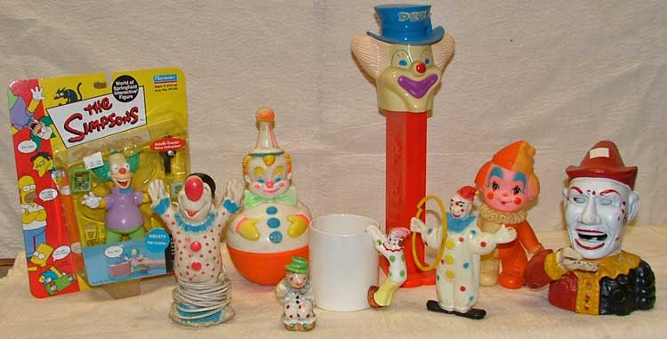 L-R The Simpsons Krusty the Clown, clown nightlight, Roly Poly clown, clown salt shaker, clown cup, giant clown PEZ dispenser - Peter Pez, plastic clown with hoop, squeak toy clown, cast-iron clown bank