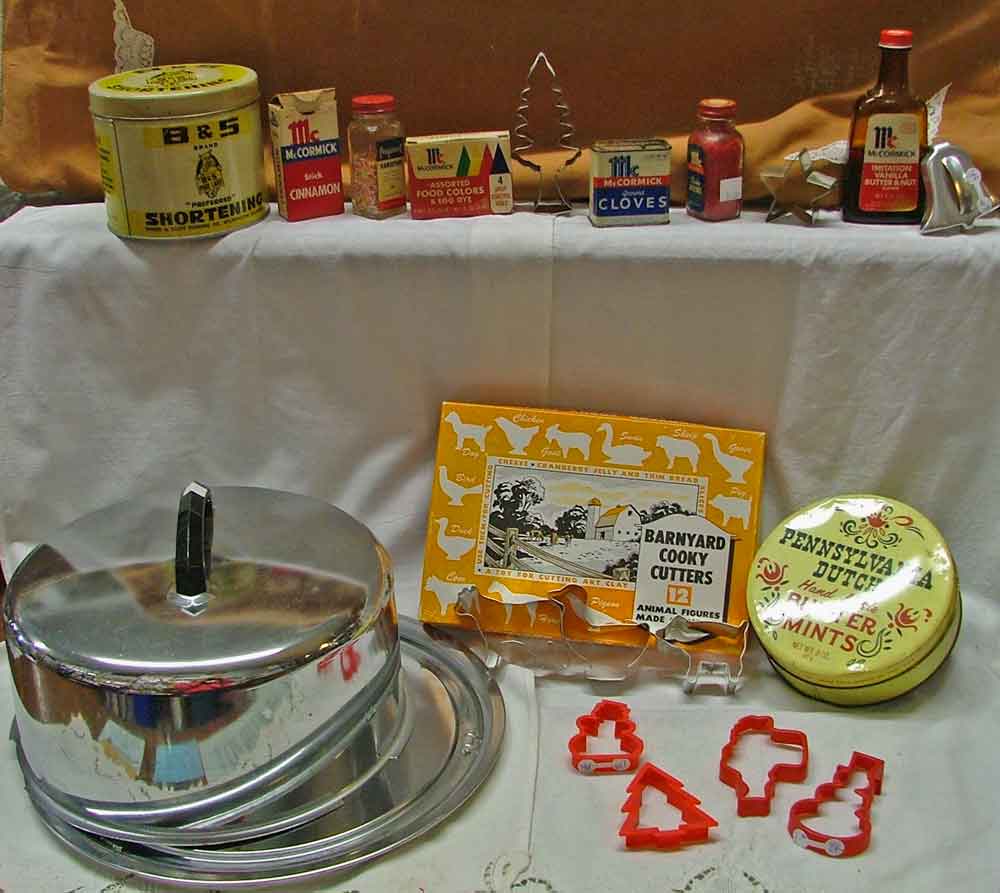Baking memorabilia including B&S brand shortening tin, old spices and food coloring, a variety of metal and plastic cookie cutters, a cake platter and cover, and a PA Dutch handmade Butter Mints tin