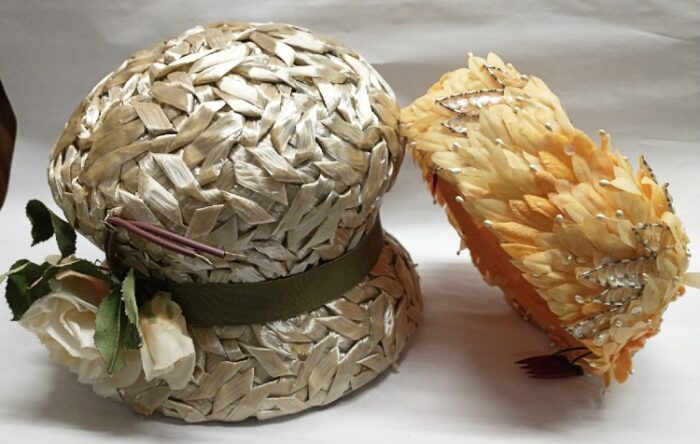 Beige straw women's cloche with green band and white flower and a yellow feathered pillbox - both available at Bahoukas