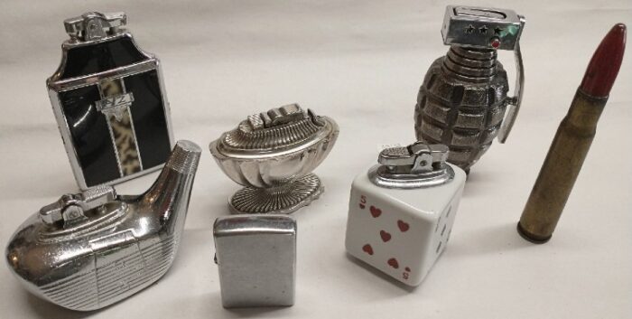 Variety of tabletop novelty lighters: military shell, Zippo, and cigarette case with lighter