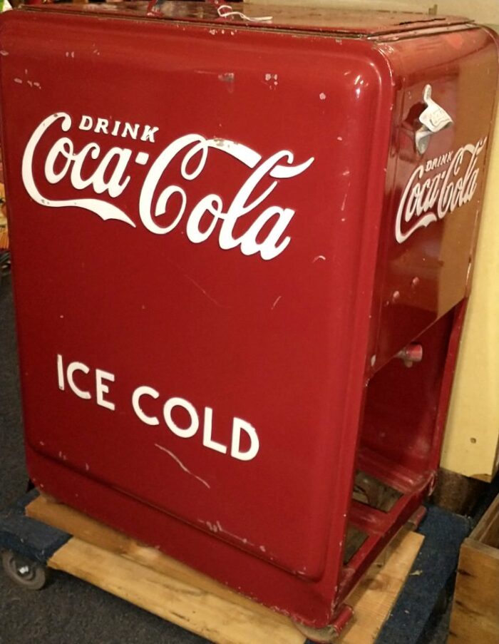Larger Coca-Cola cooler with room to store wood crates underneath.