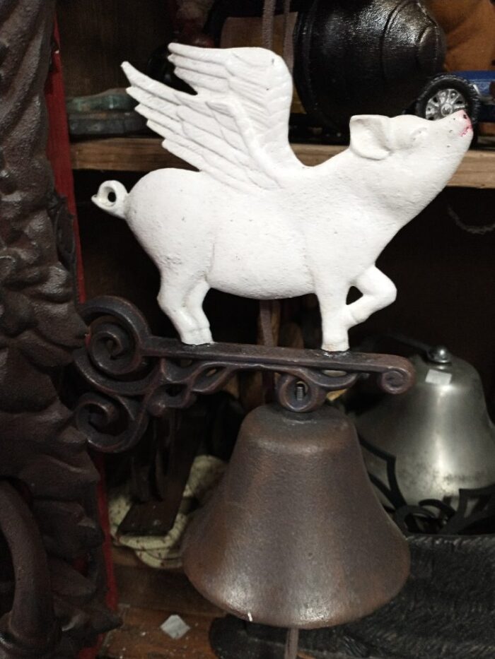 cast iron dinner bell topped with a white flying pig