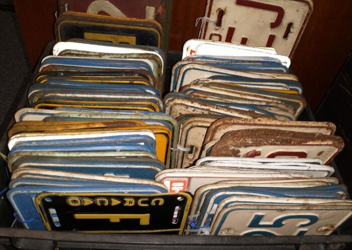 collection of old license plates in a milk crate